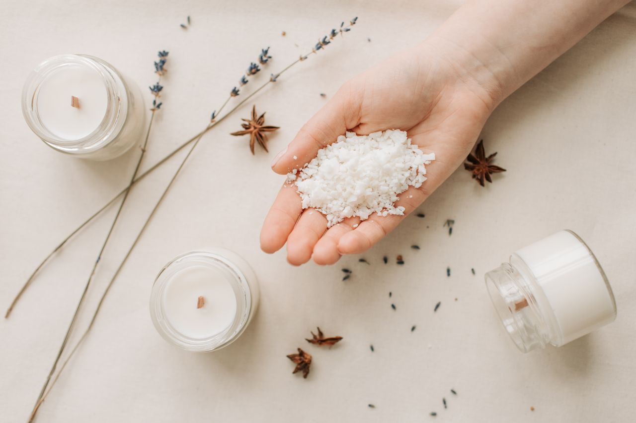 Home Flat lay of natural candle making with granulated wax, star anise, and lavender on a beige background.